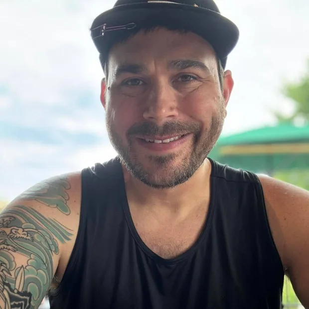 Ben Schuh smiling at an outdoor table in a backwards cap